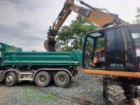 Pelle rail-route chargeant un camion benne en formation.