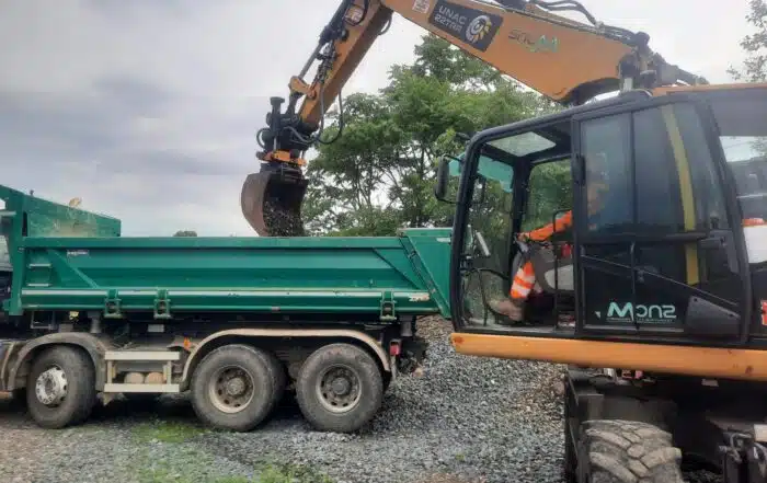 Pelle rail-route chargeant un camion benne en formation.